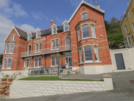 A large red brick building with multiple windows and a small balcony at Beaulieu House in Llandudno