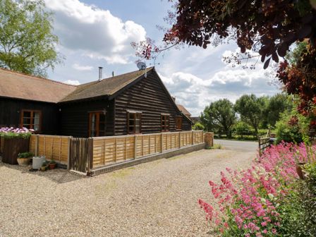 A house with a fence and flowers in the garden at Robbie's Barn, Fulready near Stratford-upon-Avon