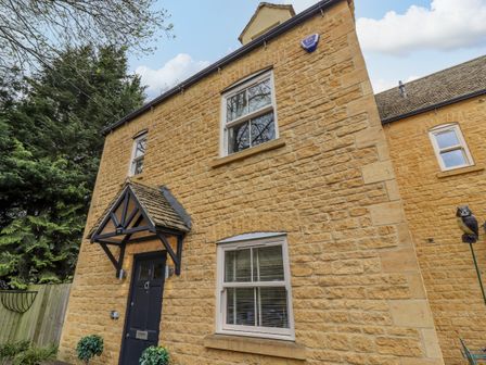 The front of a two-story stone house with a black door and two windows at Church View in Bourton-On-The-Water