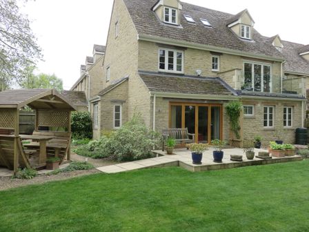 A stone house with a garden patio and wooden gazebo in a green lawn at 5 Burford Mews in Burford