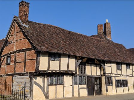 A historic timber framed building with leaded windows and a tiled roof at One Masons Court in Stratford upon Avon