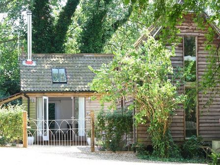 A wooden house with large windows and a small garden with bushes in front at The Linhay in Little Coxwell near Faringdon