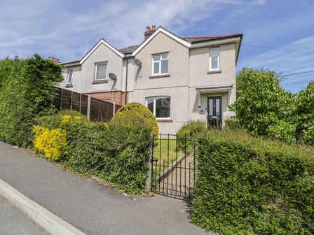 A semi detached house with shrubs and a metal gate in front at Arnant in Dolgellau