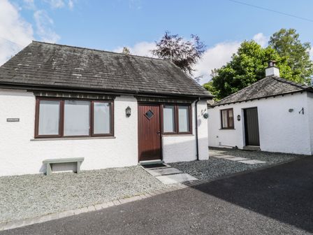 A white building with a dark door and windows beside a smaller white outbuilding at Gerand in Ambleside