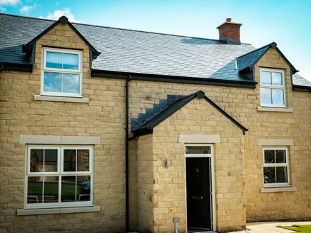 The exterior of a stone house with windows and a black door numbered 10 at Oystercatcher in Embleton