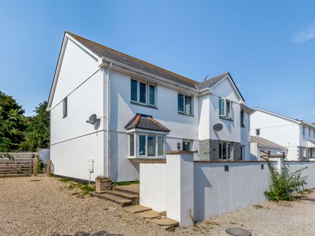 A white two-story house with stone steps and a gravel driveway at 8 Harlyn Mews in Harlyn Bay Cornwall