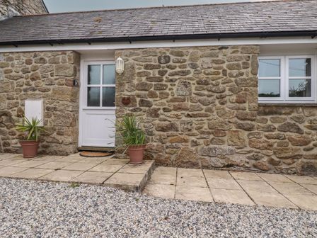 A stone wall with a door and window at The Smithy in Blisland