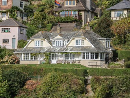 A house with multiple windows and a stone roof surrounded by greenery at Timbers in Newton Ferrers