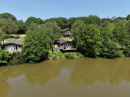 An outdoor area with cabins near a lake at 4 Water's Edge in Lanreath
