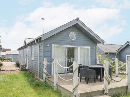 A wooden cabin with a small deck and outdoor table and chairs at Sea Breeze The Bay near Filey