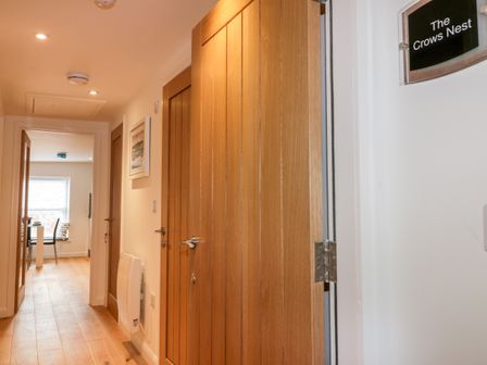 A hallway with wooden doors and a dining area visible at The Crows Nest in Mevagissey