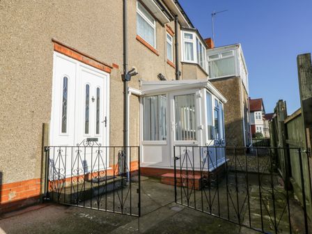 The exterior entrance of a house with a white door a white conservatory enclosed by a black metal gate at Southpoint in Bridlington