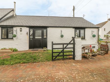 A white cottage with black doors and windows and a small black gate in front at Cowslip Cottage in Rosemarket