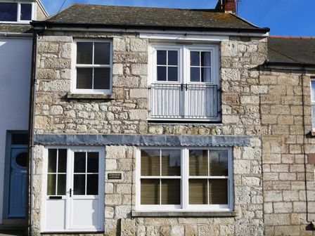 Front view of a stone cottage with white framed windows and door at Alpen Rose Cottage Easton Portland