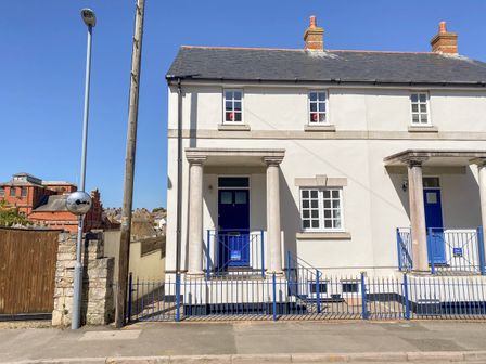 A white semi detached house with blue doors and a blue fence under a clear sky at Ashwood Brewers Quay Harbour
