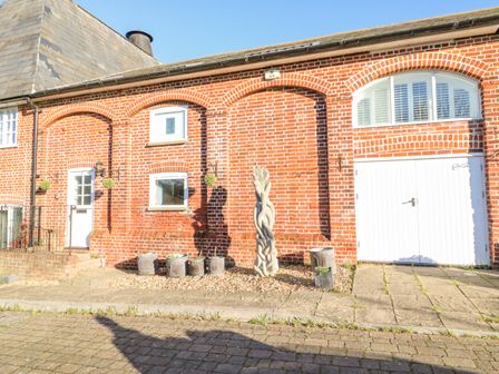 A brick exterior with white doors windows hanging plants and a sculpture at Barley Mews Brewers Quay Harbour