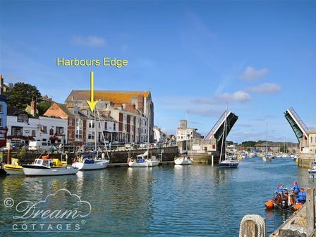 A harbor with boats docked near buildings and a raised drawbridge at Harbours Edge in Brewers Quay Harbour