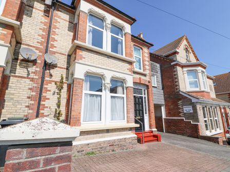 Front view of a brick house with decorated windows and a black door with red steps and a driveway at Gone Fishing in Brewers Quay Harbour