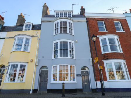 Exterior view of three adjacent terraced houses with bay windows and chimneys at Harbourside House in Brewers Quay Harbour