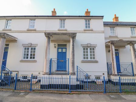 Exterior view of a white townhouse with blue doors and railings and stone columns at Hops House in Brewers Quay Harbour