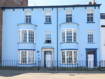 A blue building with bay windows and two white doors behind a black metal fence at Brewers Quay Harbour