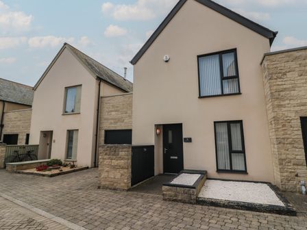 Two beige houses with black doors and windows on a paved street at Jurassic Coast House in Portland