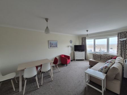 A living room with a sofa and dining area at Jurassic View West Bay