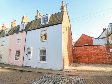 A row of terraced houses on a street with paved sidewalk and cobblestone road at Lobster Cottage Brewers Quay Harbour