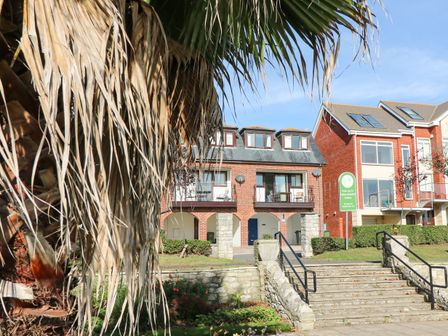 A building with balconies and stairs in front with a palm tree on the side at Lookout in Cove Castle