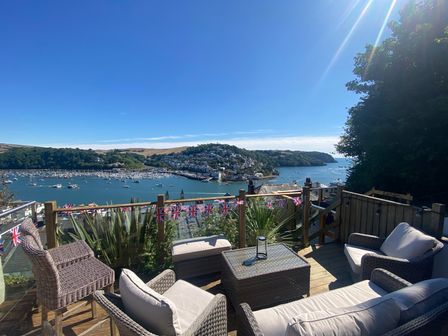 A deck with wicker furniture overlooking a harbor with boats and a hillside town at Harbour Heights in Dartmouth