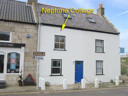 A white two-story building with a blue door and black framed windows labeled Neptune Cottage in Fortuneswell