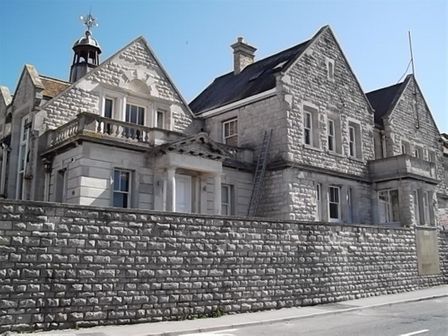 An old stone building with multiple gables and windows behind a stone wall at The Old Portland Courthouse in Portland