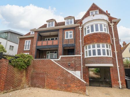 A brick residential building with multiple windows a gated entrance and a small staircase at Ocean Watch 1 in Greenhill