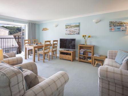 A living room with sofas a dining table TV and bookshelf at Bakers Dozen 13 Dartmouth House in Dartmouth