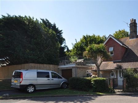 A driveway with a silver van parked next to a house with a garage and trees at Redcliff View Lodge in Weymouth