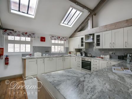 A kitchen with white cabinets marble countertops skylights and floral curtains at Upsidedown House Brewers Quay Harbour