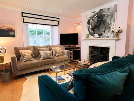 A living room with two sofas a glass coffee table a fireplace and a television at 16 Courtenay Street in Salcombe