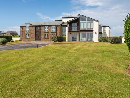 A building with large windows and a lawn in front at 2 Ocean's Edge in Thurlestone