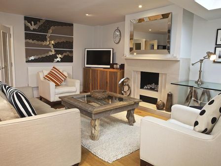 A living room with a fireplace glass coffee table armchairs and a television at Diddly Squat 43 Dart Marina in Dartmouth