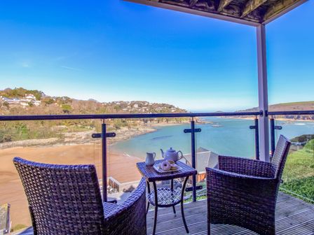 A balcony with a table and chairs overlooking the sea at 4 Bolt Head Salcombe
