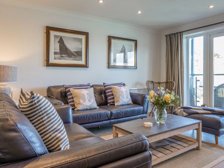 A living room with leather sofas striped and anchor cushions and a coffee table with flowers at 6 Bolt Head in Salcombe