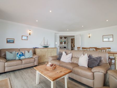 A living room with sofas and a table at 7 Thurlestone Rock in Thurlestone