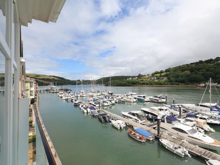 A marina with docks and multiple boats on water with hills and houses in the background at 9 Dart Marina in Dartmouth