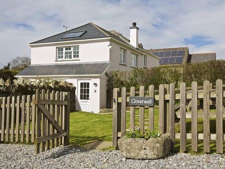 A white two-story house with a wooden fence gate and a stone planter at Cloverwell in Woodleigh