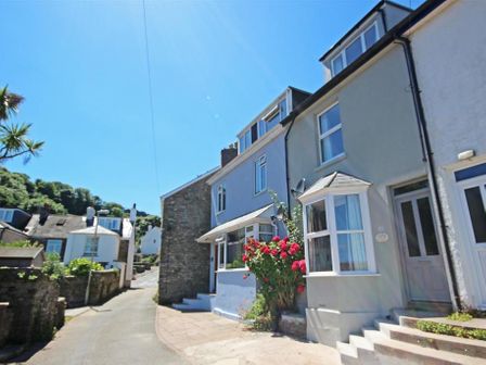A street view with houses and rose bushes along a narrow road at Crab Cottage in Salcombe