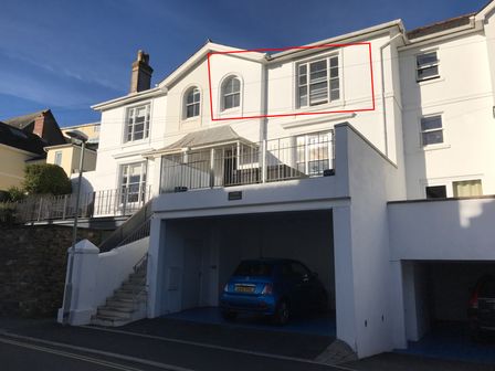 A white multi story building with stairs and parked cars under at Upper Fernlea in Salcombe