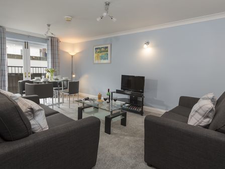 A living room with two sofas a glass coffee table a dining table and chairs and a TV at Freshford 3 Dartmouth House Dartmouth