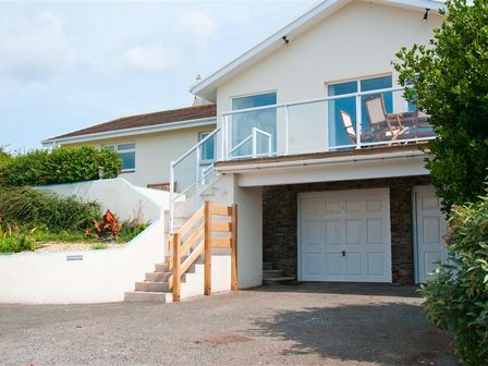 A two-level house with a garage below and a balcony with patio chairs at Greystone in Hope Cove