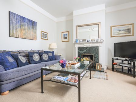 A living room with a blue sofa cushions coffee table fireplace and television at Harbourfield in Salcombe