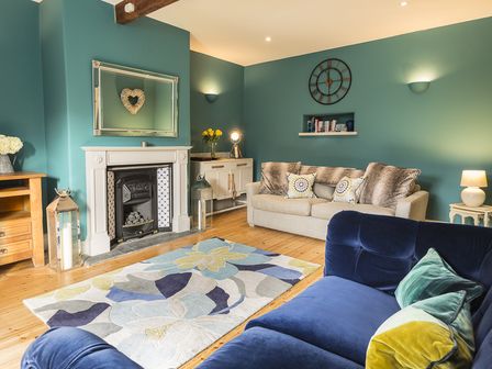 A living room with blue and beige sofas a fireplace a rug and wooden furniture at Rosemary Cottage in Goveton
